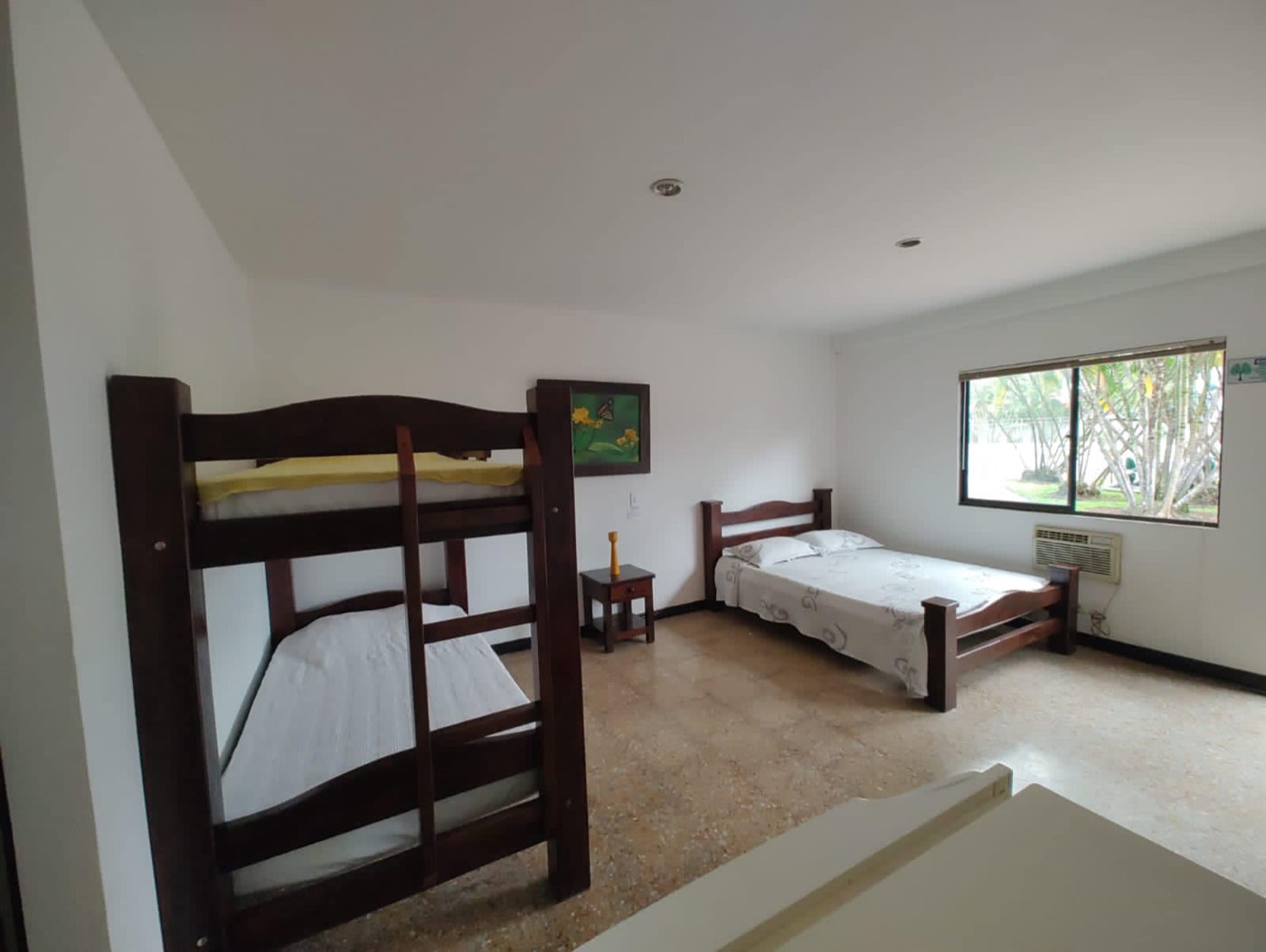 Habitación del hotel de Las Pirámides con aire acondicionado y ventana hacia las palmeras